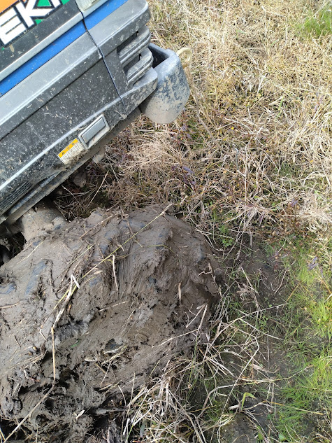 前進で引き出しを試みるトラクターの泥が詰まった右前輪