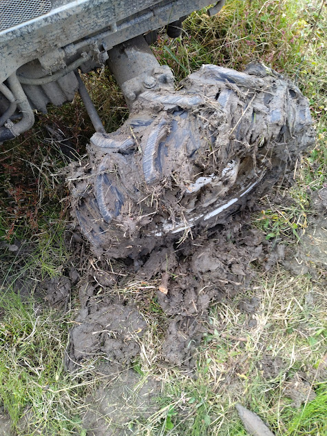 前進で引き出しを試みるトラクターの泥を枝木で取り除いた右前輪