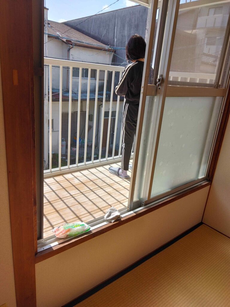 窓の修繕の間、娘にペンキの粉がふいたベランダ柵を拭いてもらう