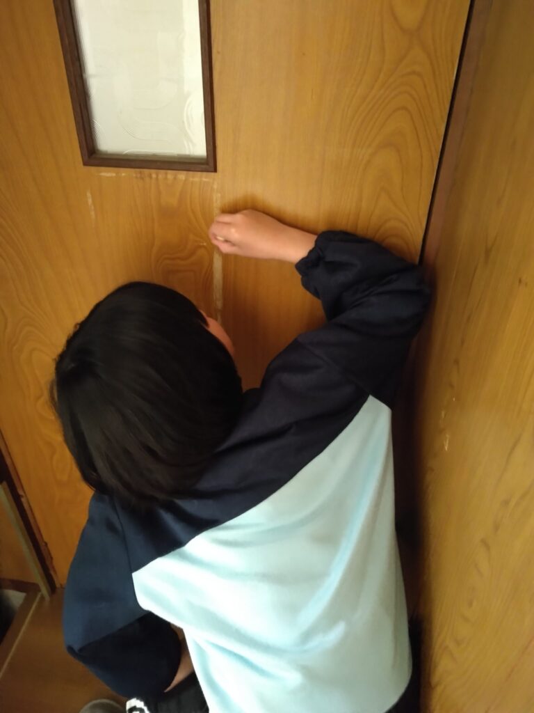 ドアを修正ペンで補修する娘