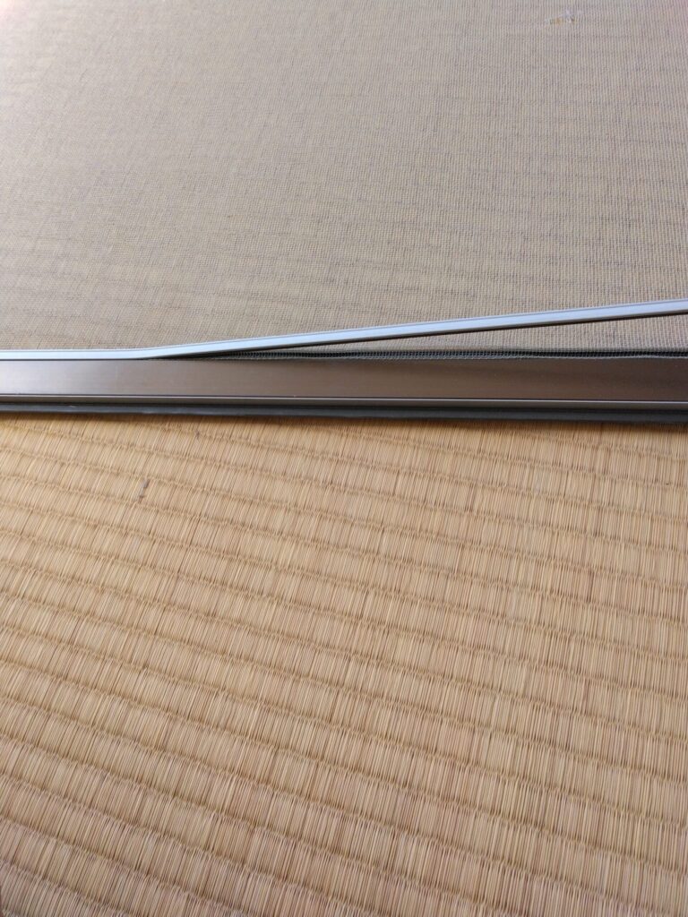 網戸の留め具の取っ掛かりを引き上げられたら上に引っ張って外していきます