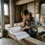 Person in work apron reviewing construction plans at a renovation site